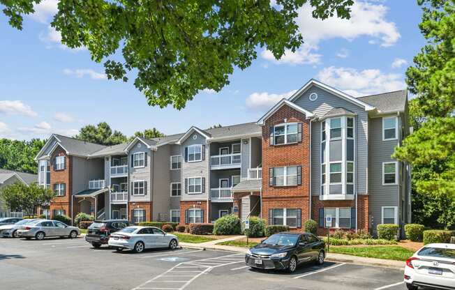 an apartment building with cars parked in a parking lot