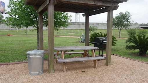 A wooden picnic table is under a wooden shelter.