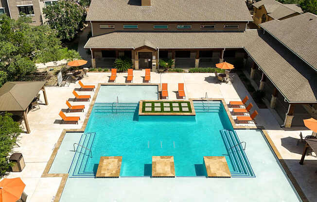 A large swimming pool surrounded by orange lounge chairs and umbrellas.