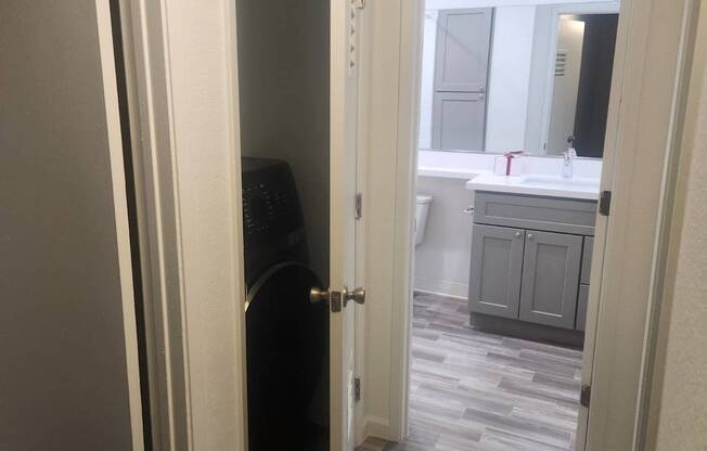 A bathroom with a sink and a mirror is visible through an open door.
