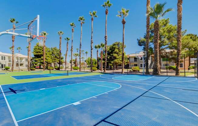 two blue basketball courts with palm trees and apartments in the background