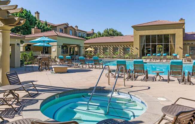 A large outdoor swimming pool with a hot tub and lounge chairs.
