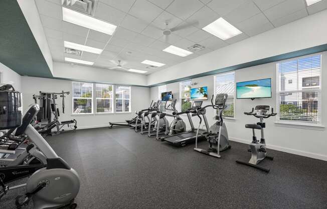 a gym with various exercise machines and windows