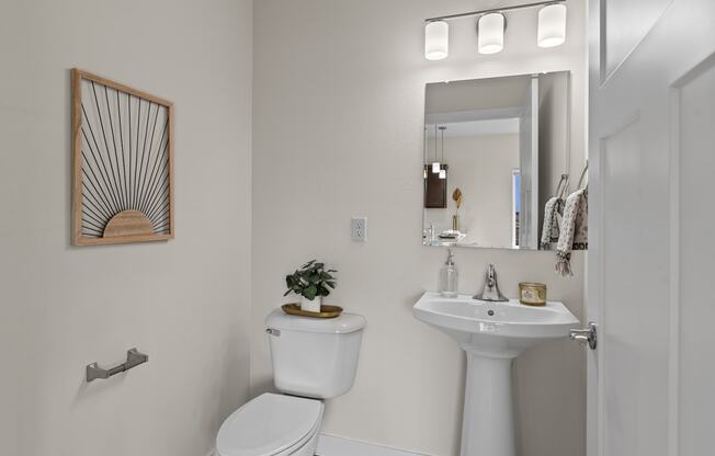 a bathroom with a toilet sink and a mirror at The Residences Apartments at Bear Tree | DeForest, WI, Wisconsin