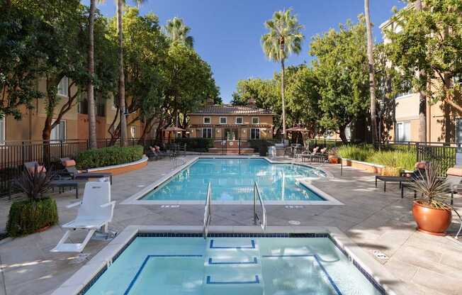 A pool surrounded by trees and chairs.