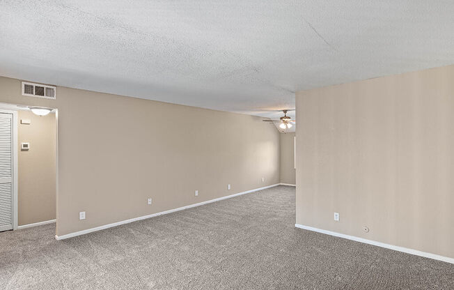 an empty living room with carpet and a door to a closet