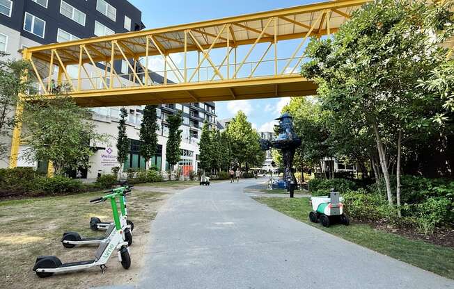 A yellow pedestrian bridge over a walkway with green scooters parked on the side. at West Inman Lofts, Georgia