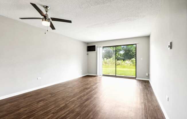 an empty living room with wood floors and a sliding glass door