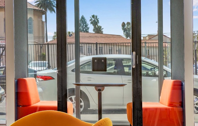 a seating area with orange chairs and a table in front of a window