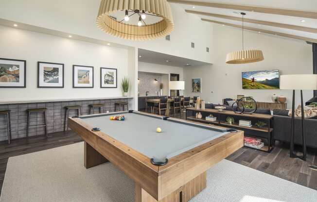 a billiards table in a clubhouse with couches and a tv