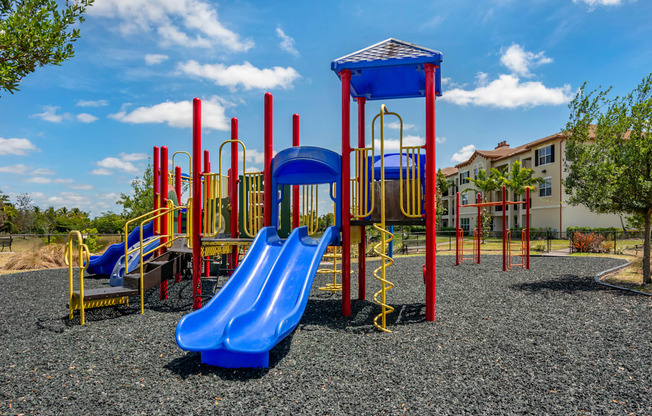 A playground with a blue slide and red and yellow play structures.