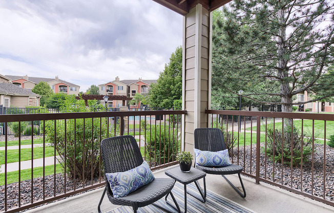 Two chairs and a small table on a balcony with a view of a residential area.
