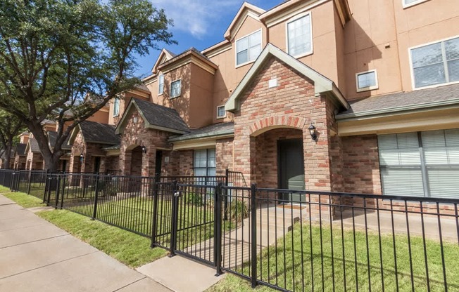 This is a photo of the townhome exteriors with a gated front yard at The Brownstones Townhome Apartments in Dallas, TX.