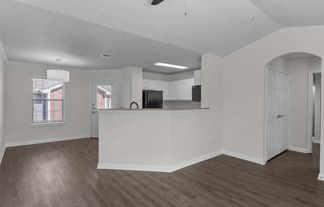 an empty living room and kitchen with a counter top and a refrigerator