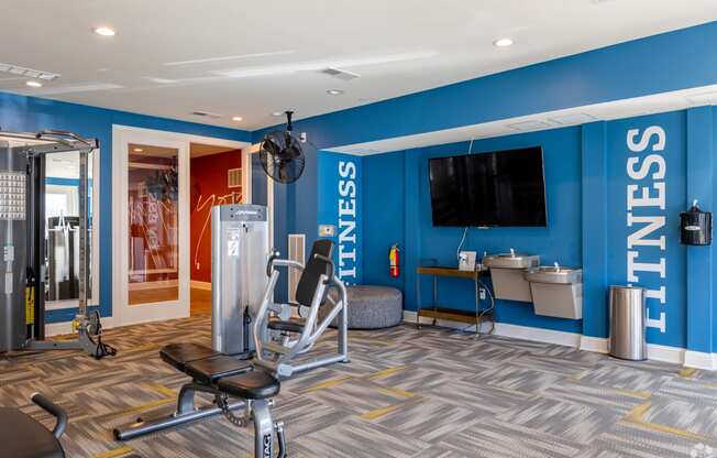 a gym with a blue wall and a tv in the corner