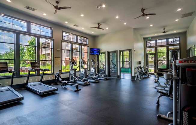 a gym with cardio equipment and windows in a building