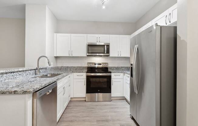 kitchen with custom white cabinetry, granite countertops, and stainless steel appliances at Sorelle apartments