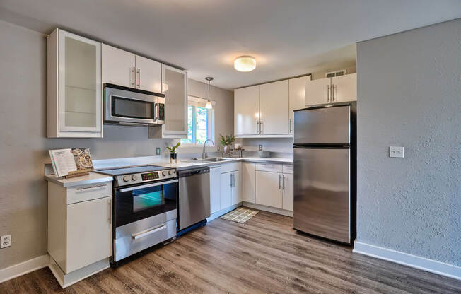 an empty kitchen with stainless steel appliances and white cabinets