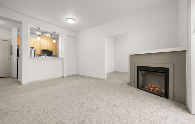 A living room with a fireplace and a kitchen area in the background.