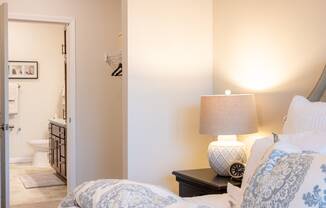 a bedroom with a bed and a lamp and a bathroom