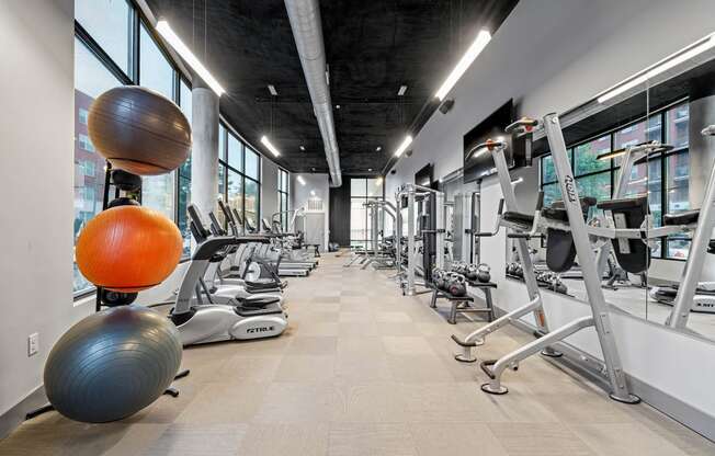 a gym with weights and other exercise equipment in a building with large windows