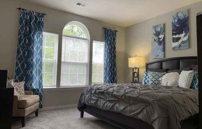 a bedroom with a bed and windows with curtains