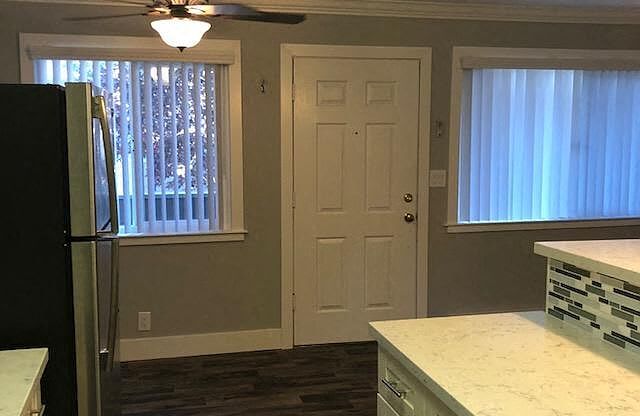 A kitchen with a black fridge and white cabinets.