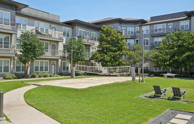 Apartment complex with a green lawn and trees.