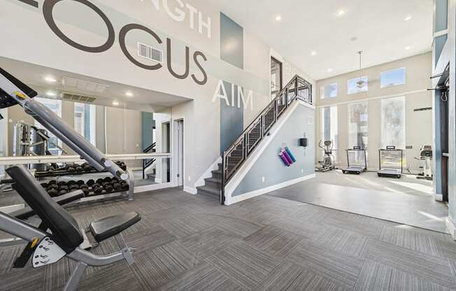 A gym with a staircase and a weight machine.