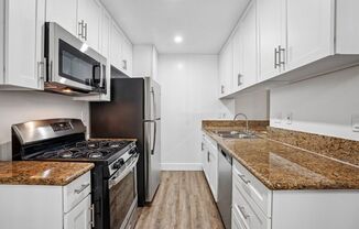 A kitchen with black appliances and granite countertops.