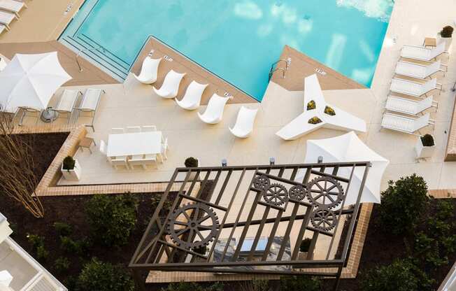 arial view of a swimming pool with white lounge chairs and umbrellas