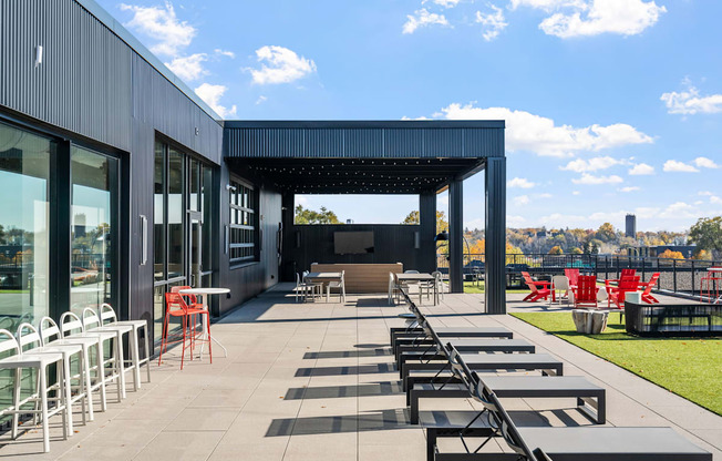an outdoor patio with tables and chairs and a black building