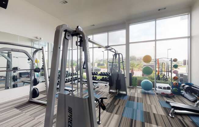 a gym with a lot of exercise equipment and large windows