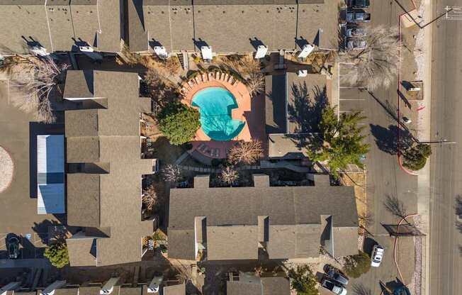 An aerial view of a swimming pool surrounded by trees and buildings.