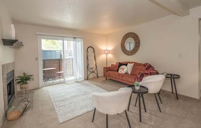 Model living room with a fireplace, a couch, two chairs, and a table at Pheasant Pointe Apartments, California, 95833