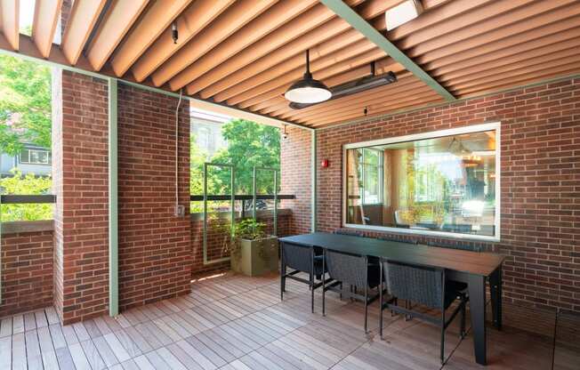 Covered red brick patio with hardwood flooring, a long table and chairs at Sylvan Uptown, Denver, CO, 80203