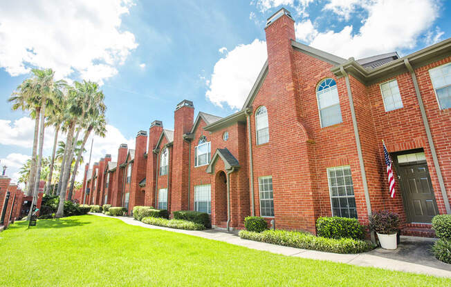 a brick building with a green lawn and palm trees