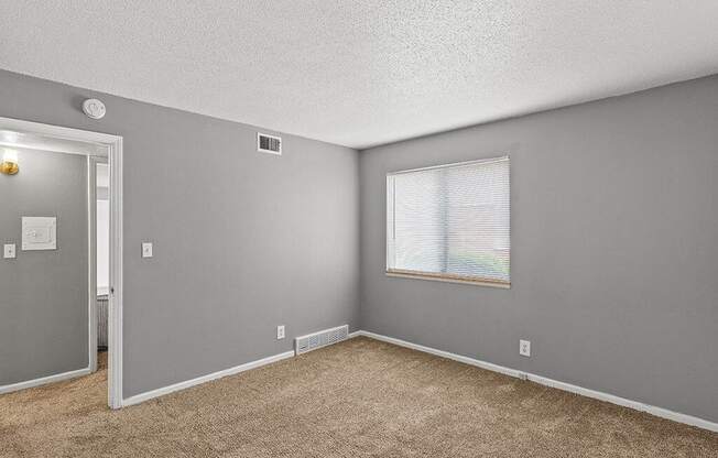 an empty living room with a window and carpet