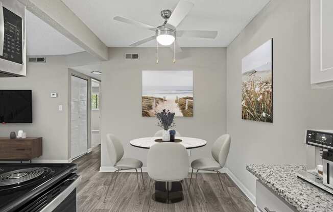 a dining area with a table and chairs and a ceiling fan