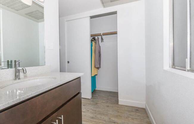 A bathroom with a sink, mirror, and wooden floor.