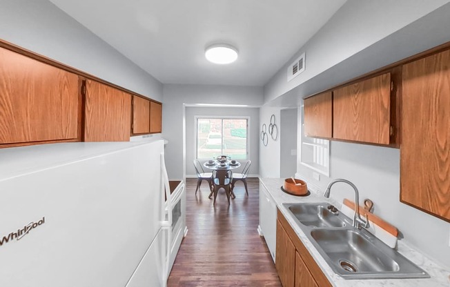 a kitchen with wooden cabinets and a sink and a dining room with a table