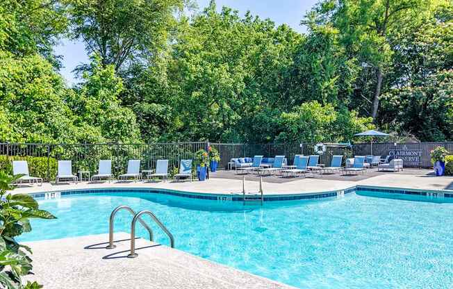 a swimming pool with chaise lounge chairs and trees