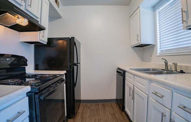 A kitchen with black appliances and white cabinets.