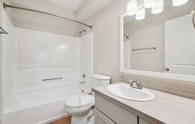 A white bathroom with a toilet, sink, and mirror.
