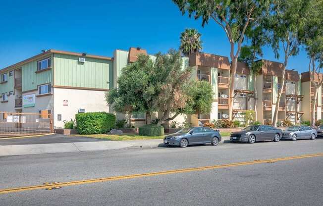 a street view of an apartment building with cars parked in front