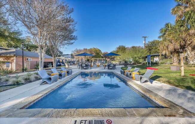 a swimming pool with chairs around it and a patio with umbrellas  at Sunset Ridge, Texas