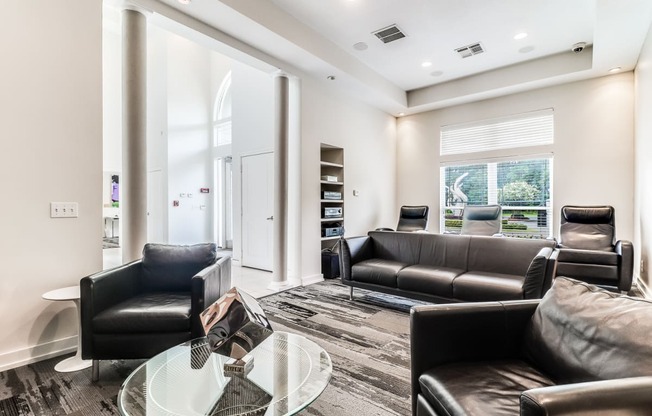 a living room with black leather couches and a glass coffee table
