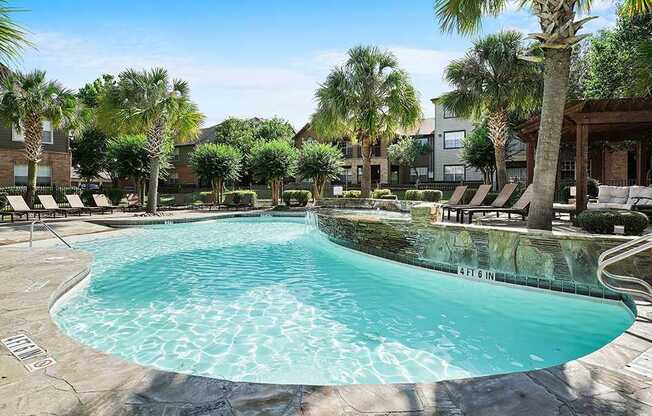 A swimming pool surrounded by palm trees and lounge chairs.