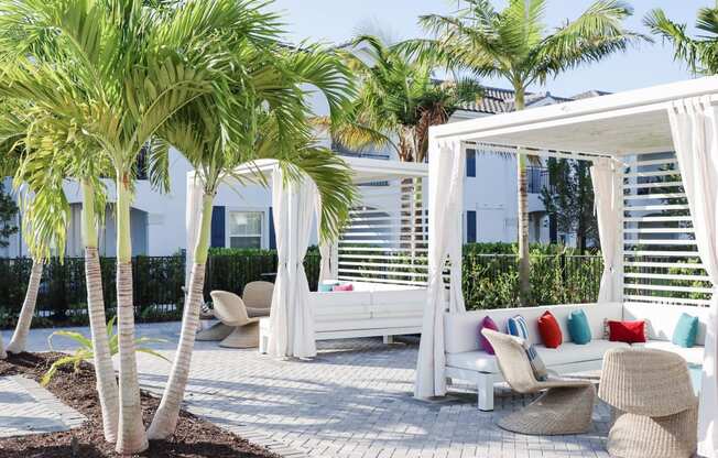 a patio with white furniture and palm trees