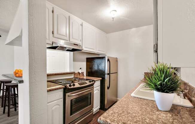 Kitchen with Stainless steel appliances including electric range over range hood, two door refrigerator, white kitchen cabinets, granite countertops